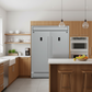 Modern kitchen with stainless steel refrigerator and oven, wooden cabinets, and a countertop with fruit.