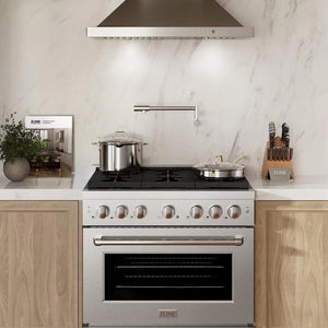 Luxurious kitchen setting with a ZLINE 36-inch gas range in DuraSnow stainless steel beneath a matching extractor hood, set against a marble backsplash. The range is adorned with a large stainless steel pot and a frying pan, positioned near a knife block and decorative kitchen items, creating a blend of functionality and style