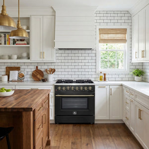 Modern kitchen with black stove, wooden island, and white cabinets.